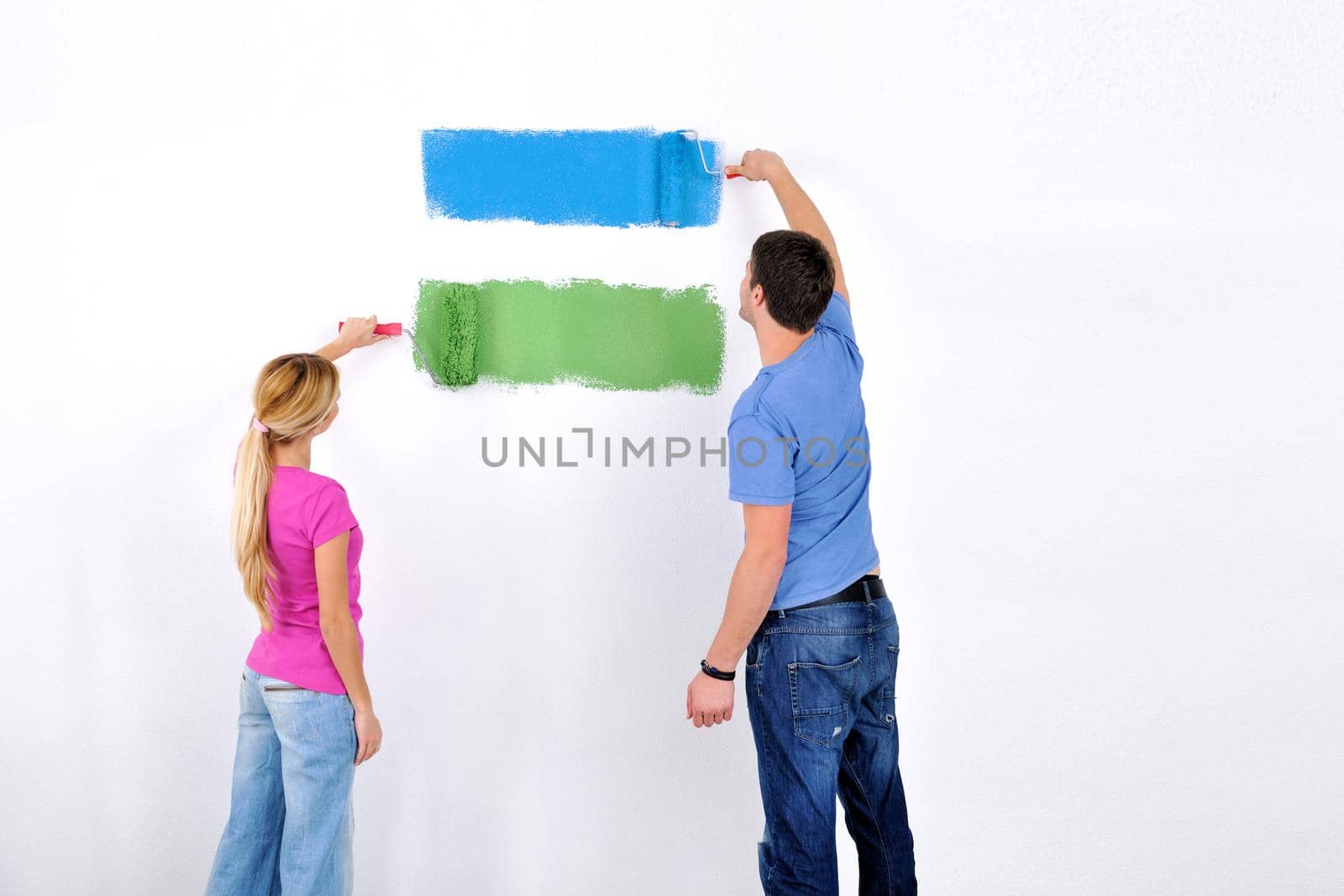 happy young couple paint in green and blue color white wall of their new home