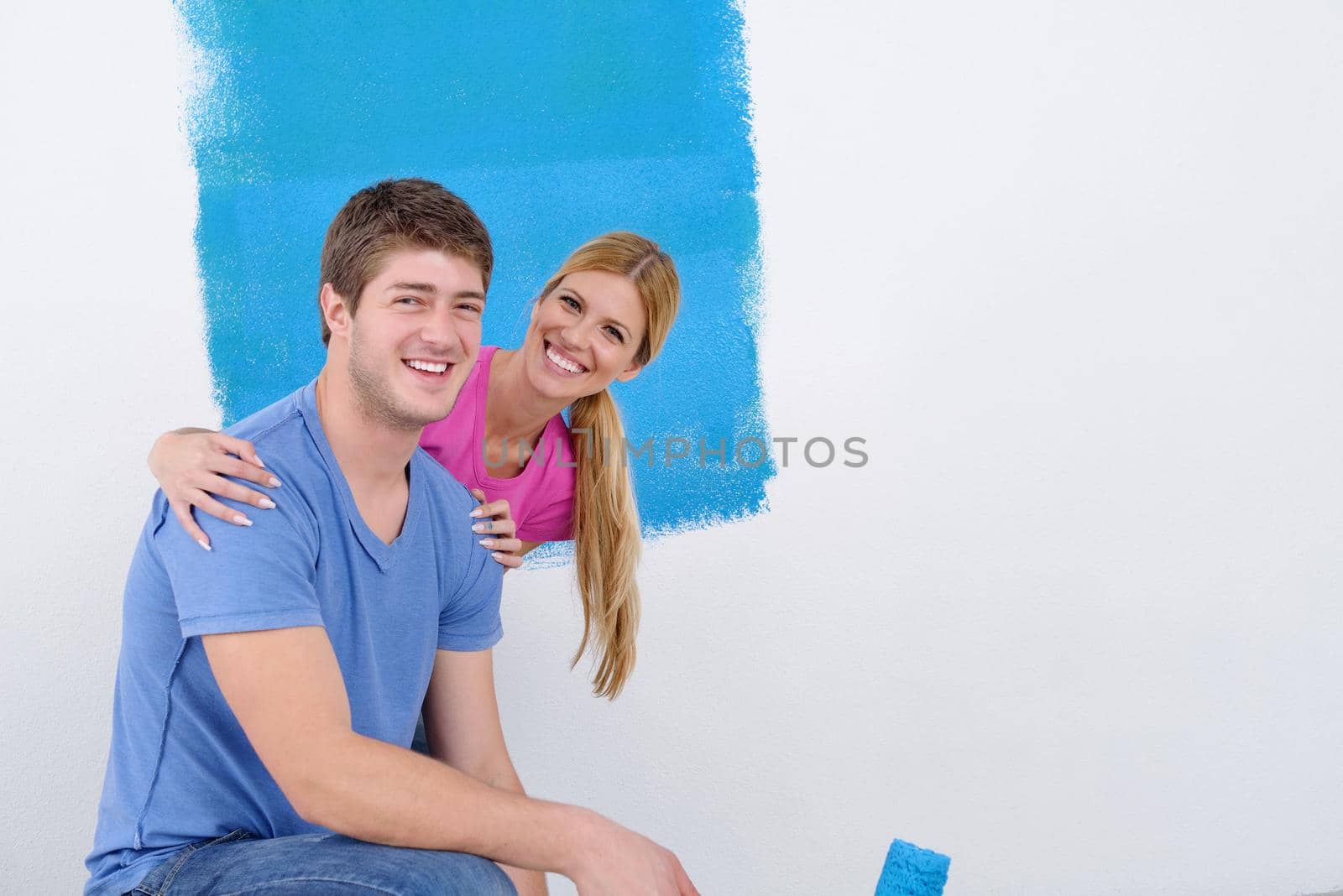 happy young couple paint in green and blue color white wall of their new home