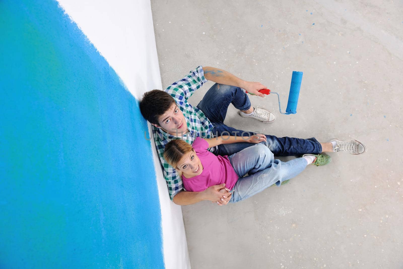 happy young couple relax after painting white wall in green and blue color in their new home