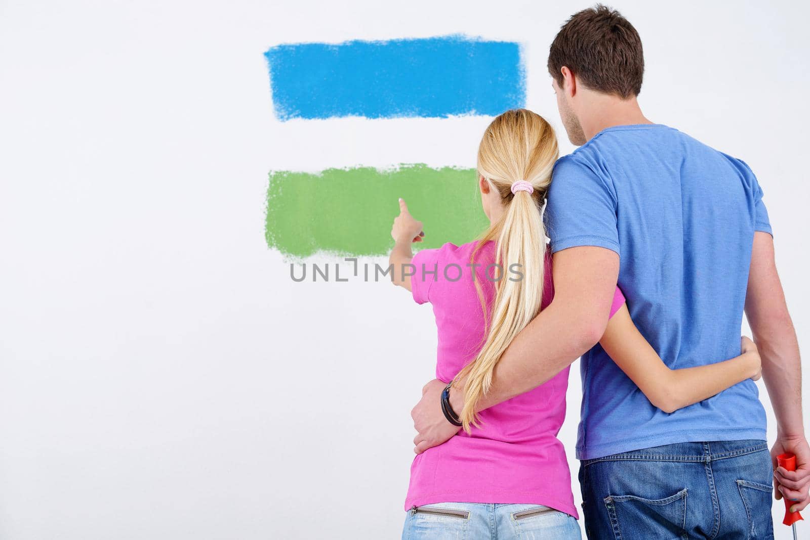 happy young couple paint in green and blue color white wall of their new home