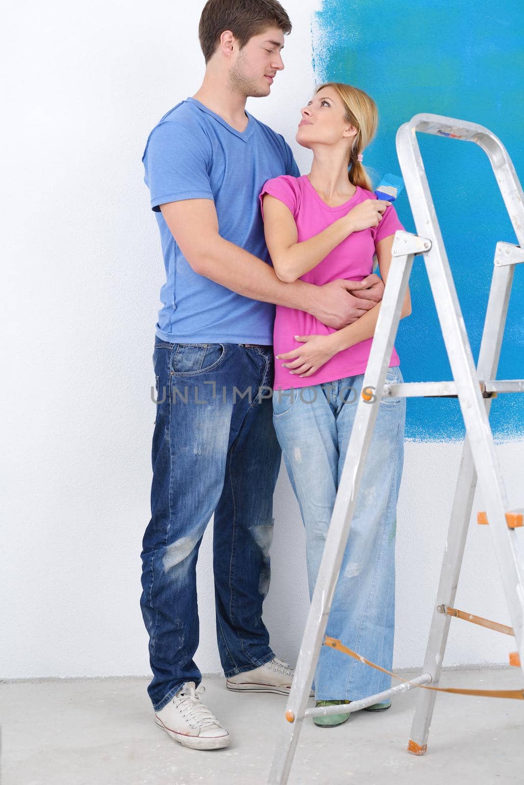 happy young couple paint in green and blue color white wall of their new home