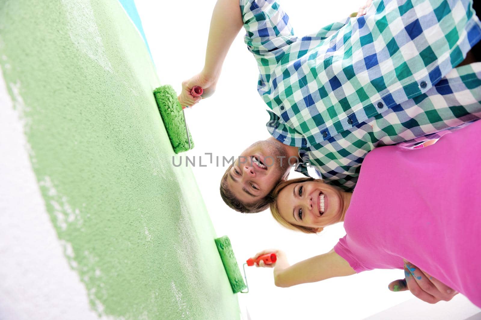 happy young couple paint in green and blue color white wall of their new home