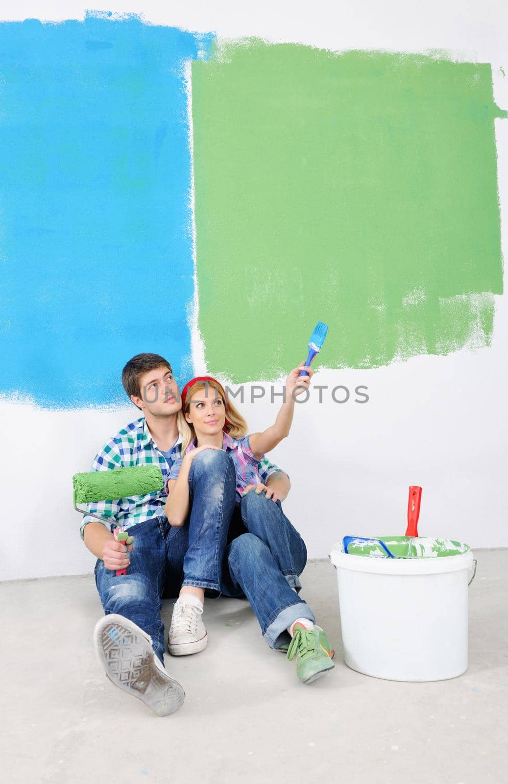 happy young couple paint in green and blue color white wall of their new home