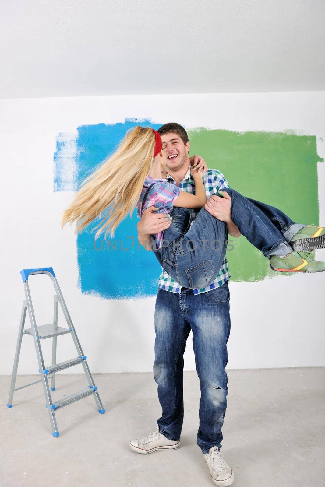 happy young couple paint in green and blue color white wall of their new home