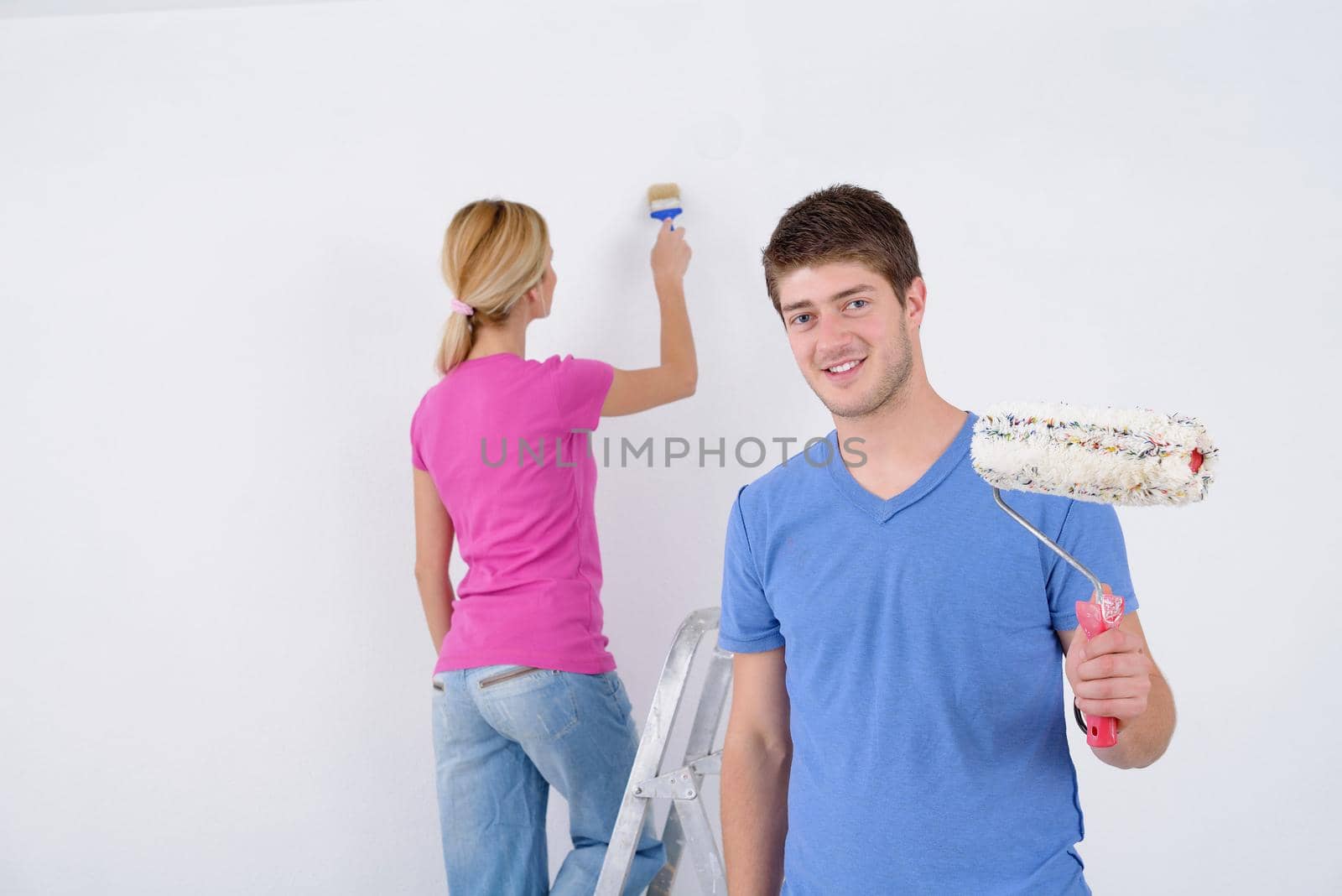 happy young couple paint in green and blue color white wall of their new home