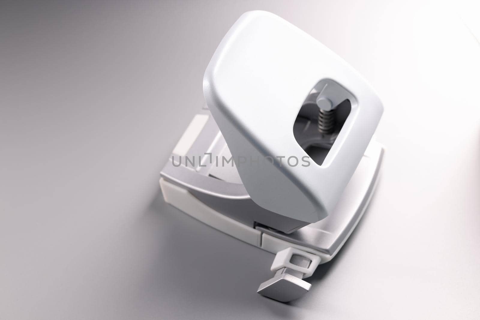 Closeup of white hole punch on gray background. Sale of stationery concept