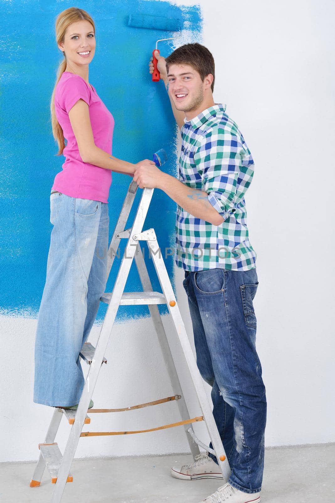 happy young couple paint in green and blue color white wall of their new home