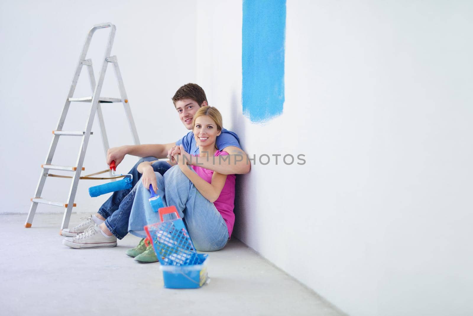 happy young couple relax after painting white wall in green and blue color in their new home