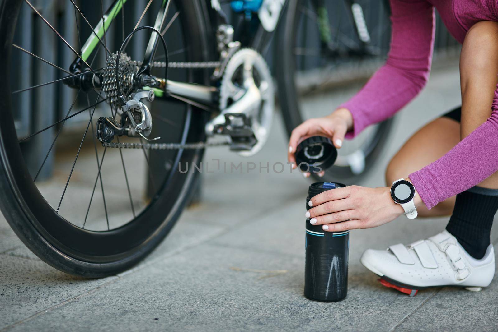Cropped shot of young woman, professional female cyclist taking pump for inflating the tire of her bicycle outdoors on a daytime by friendsstock