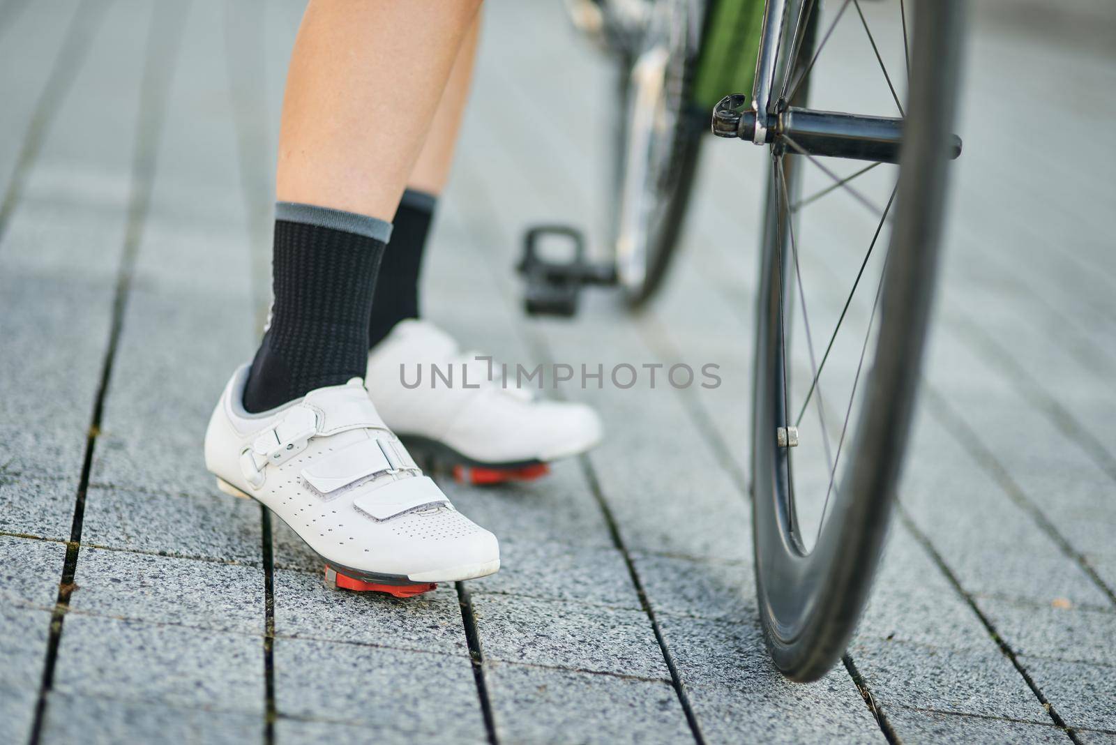 Close up shot of legs of female cyclist wearing cycling shoes standing with her bike. Active lifestyle, sports concept. Selective focus