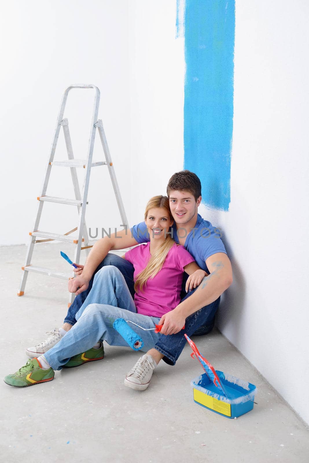 happy young couple relax after painting white wall in green and blue color in their new home