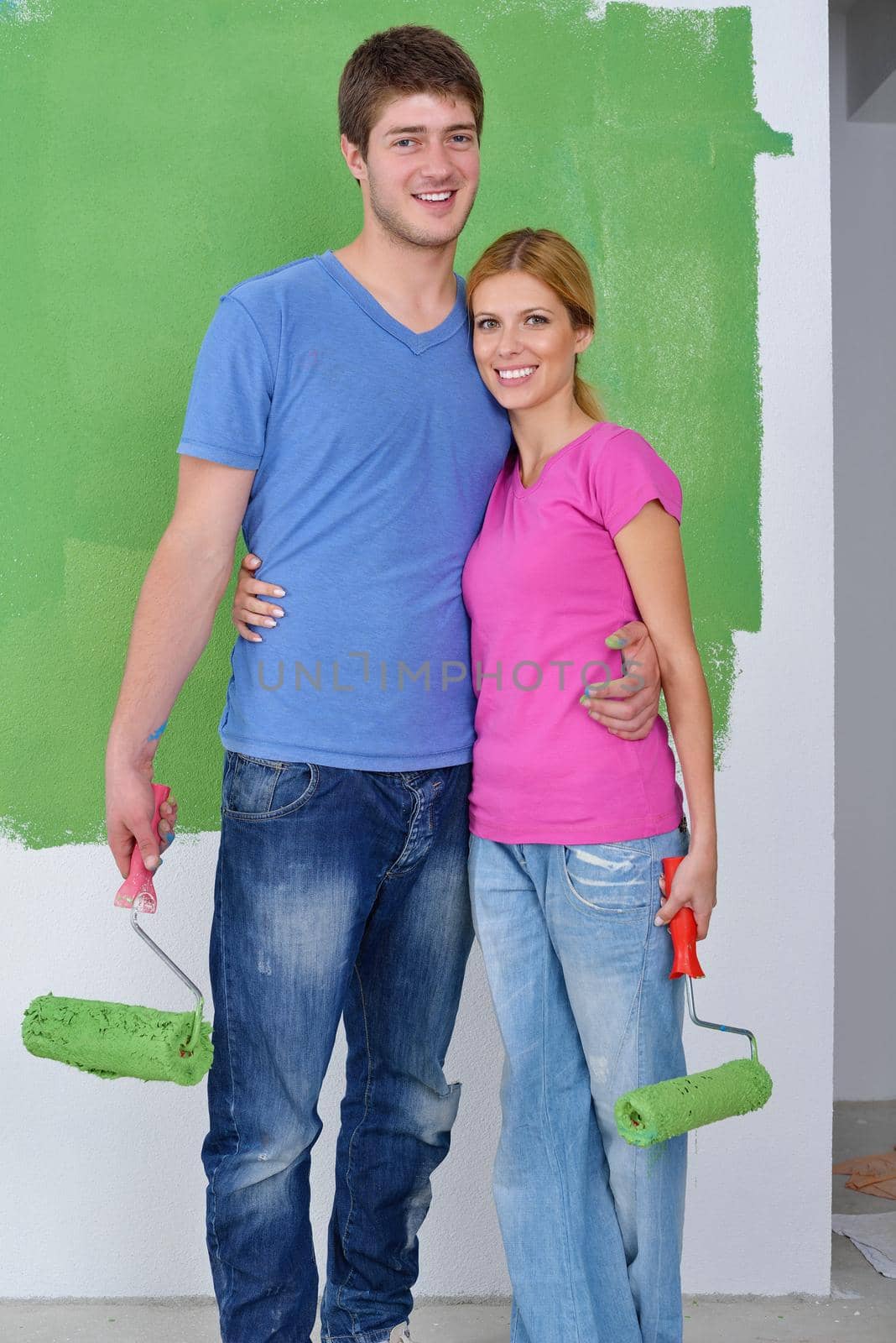 happy young couple paint in green and blue color white wall of their new home