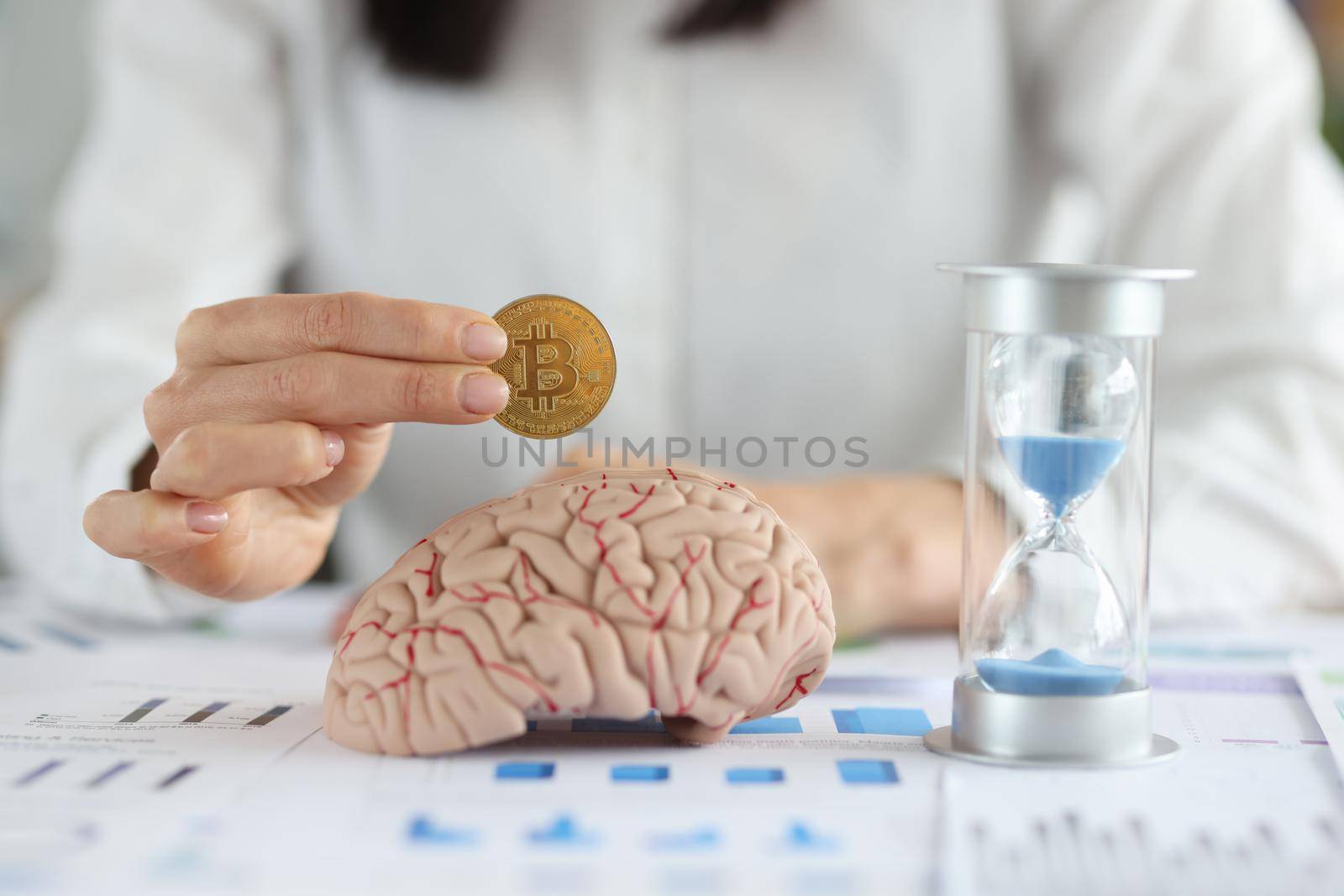 Business woman holding bitcoin coin in front of brain mockup and hourglass closeup by kuprevich