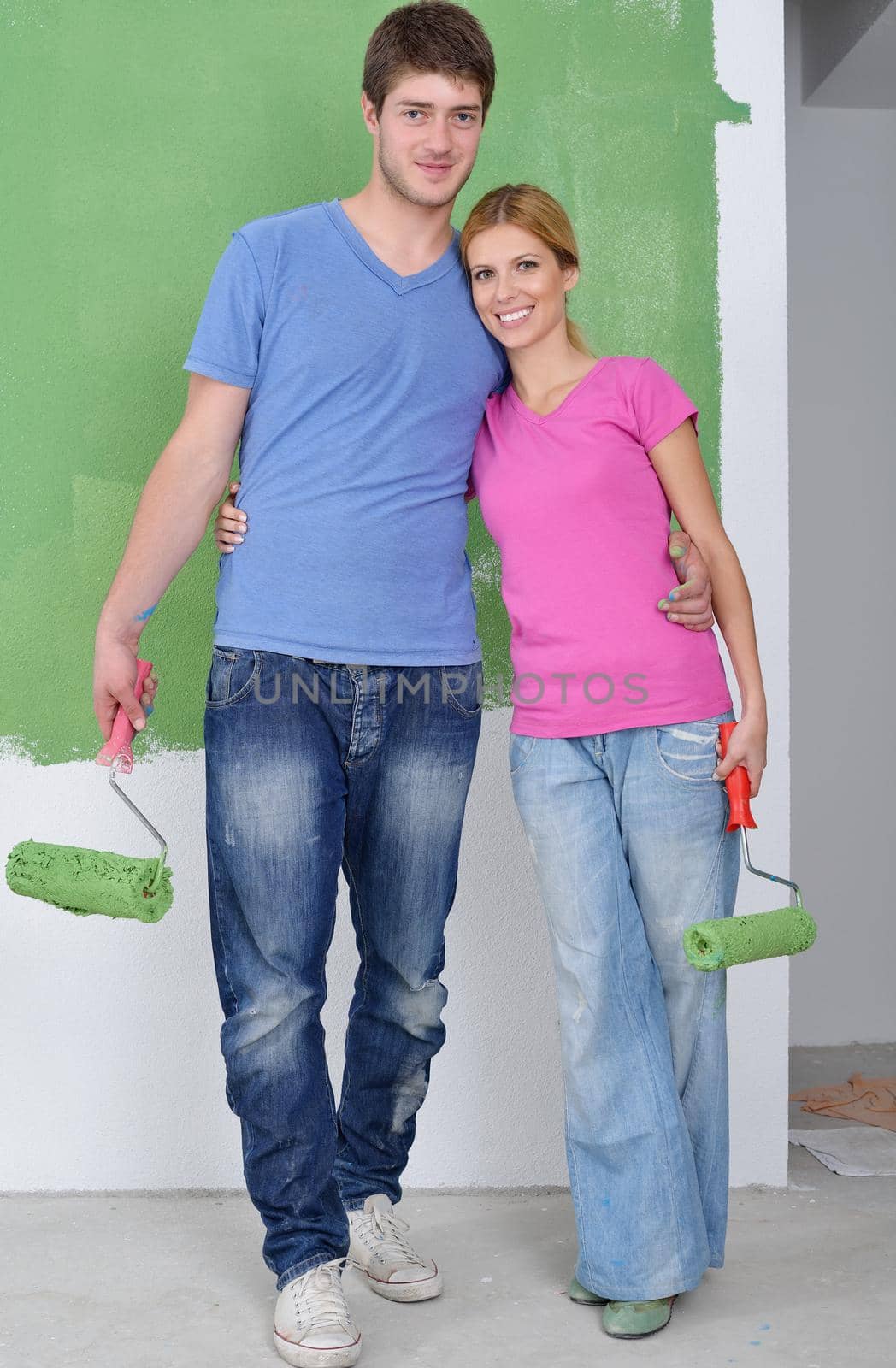 happy young couple paint in green and blue color white wall of their new home