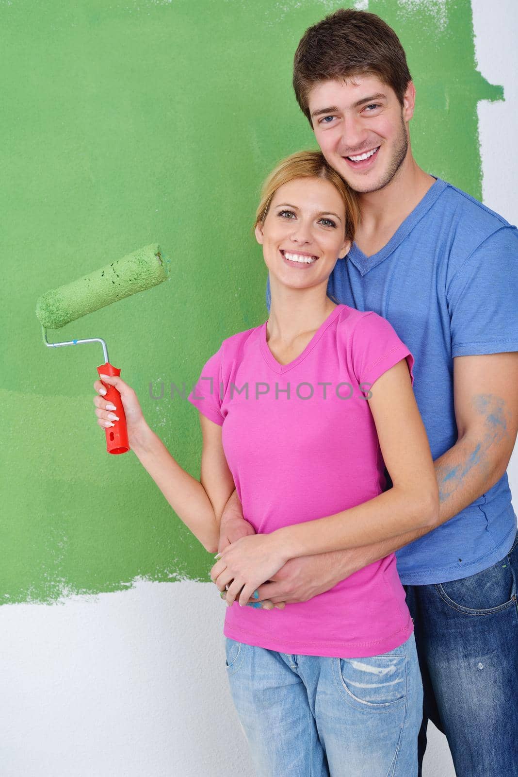 happy young couple paint in green and blue color white wall of their new home