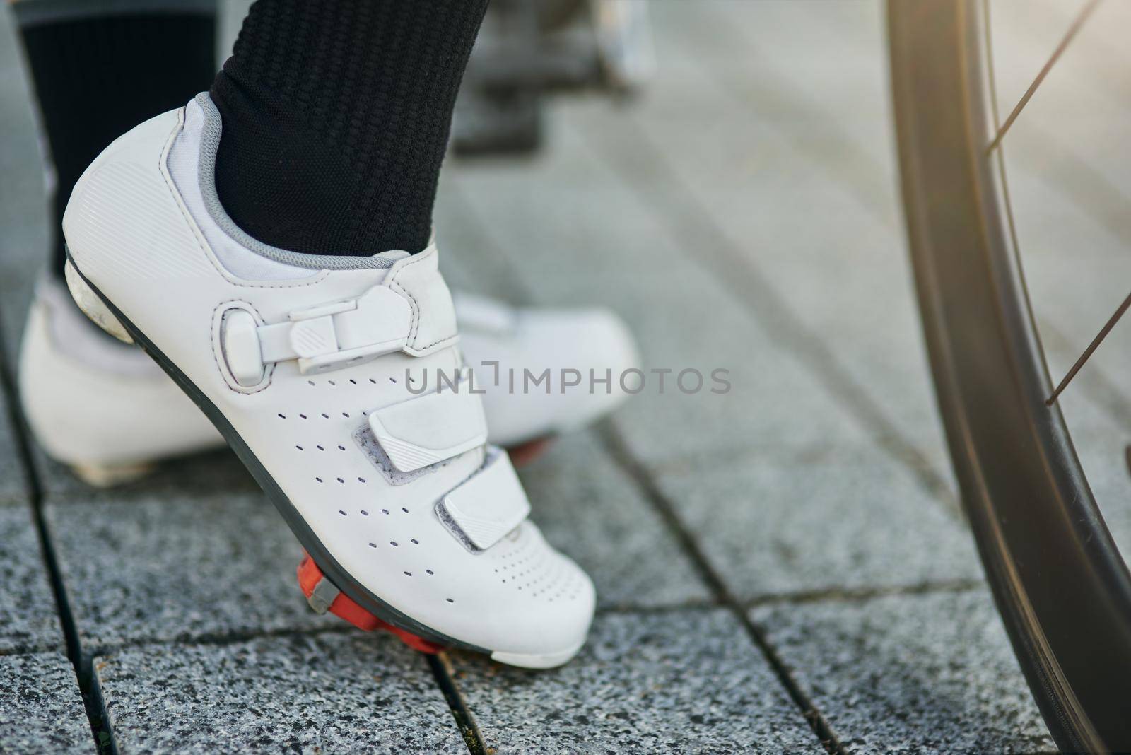 Close up shot of legs of female cyclist wearing cycling shoes standing with her bike by friendsstock