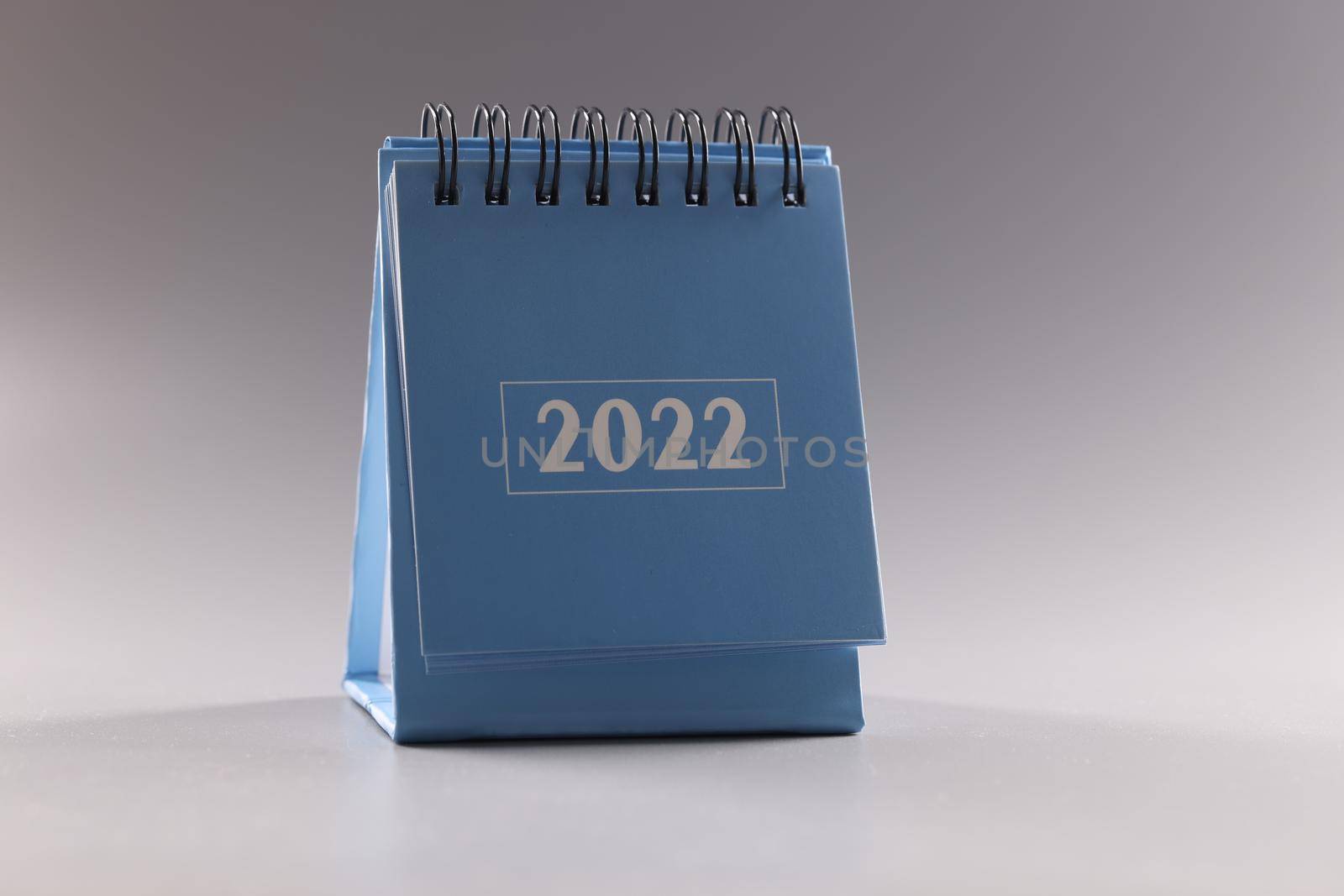 Desktop blue paper calendar for 2022 on gray background closeup by kuprevich