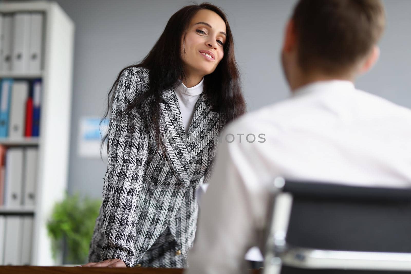 Portrait of beautiful woman in presentable suit talking to male worker on her office. Female boss flirt or explain further work plan. Business, job concept