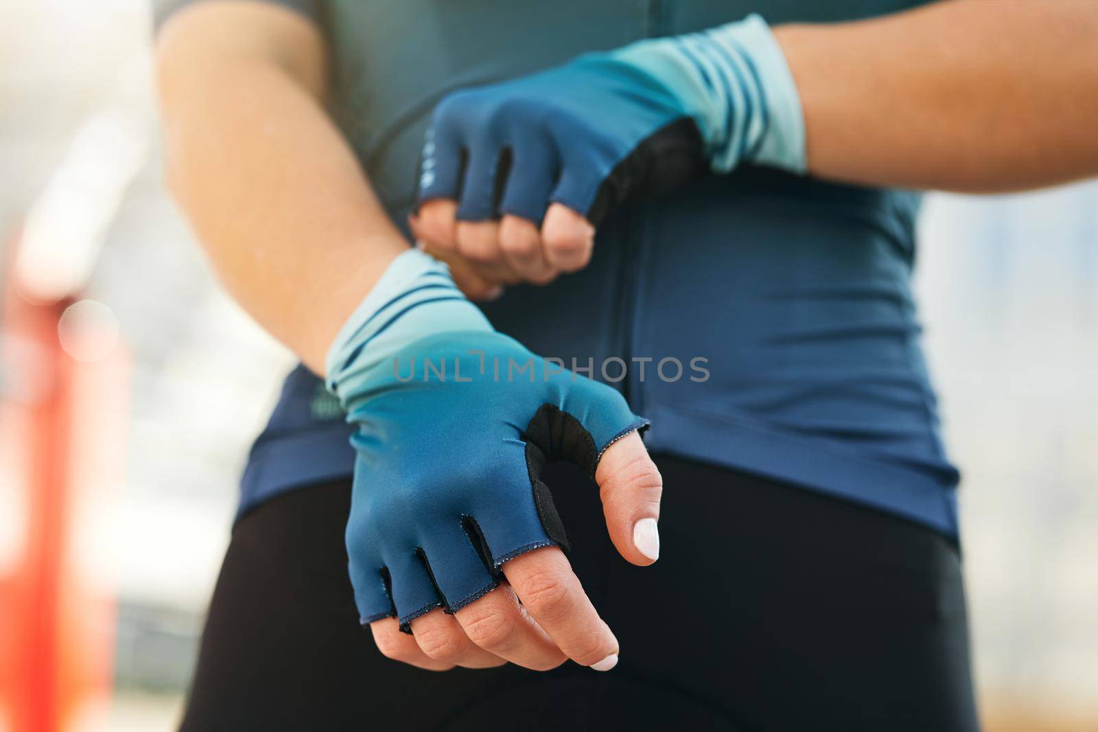 Professional female cyclist putting on cycling gloves while getting ready for training by friendsstock