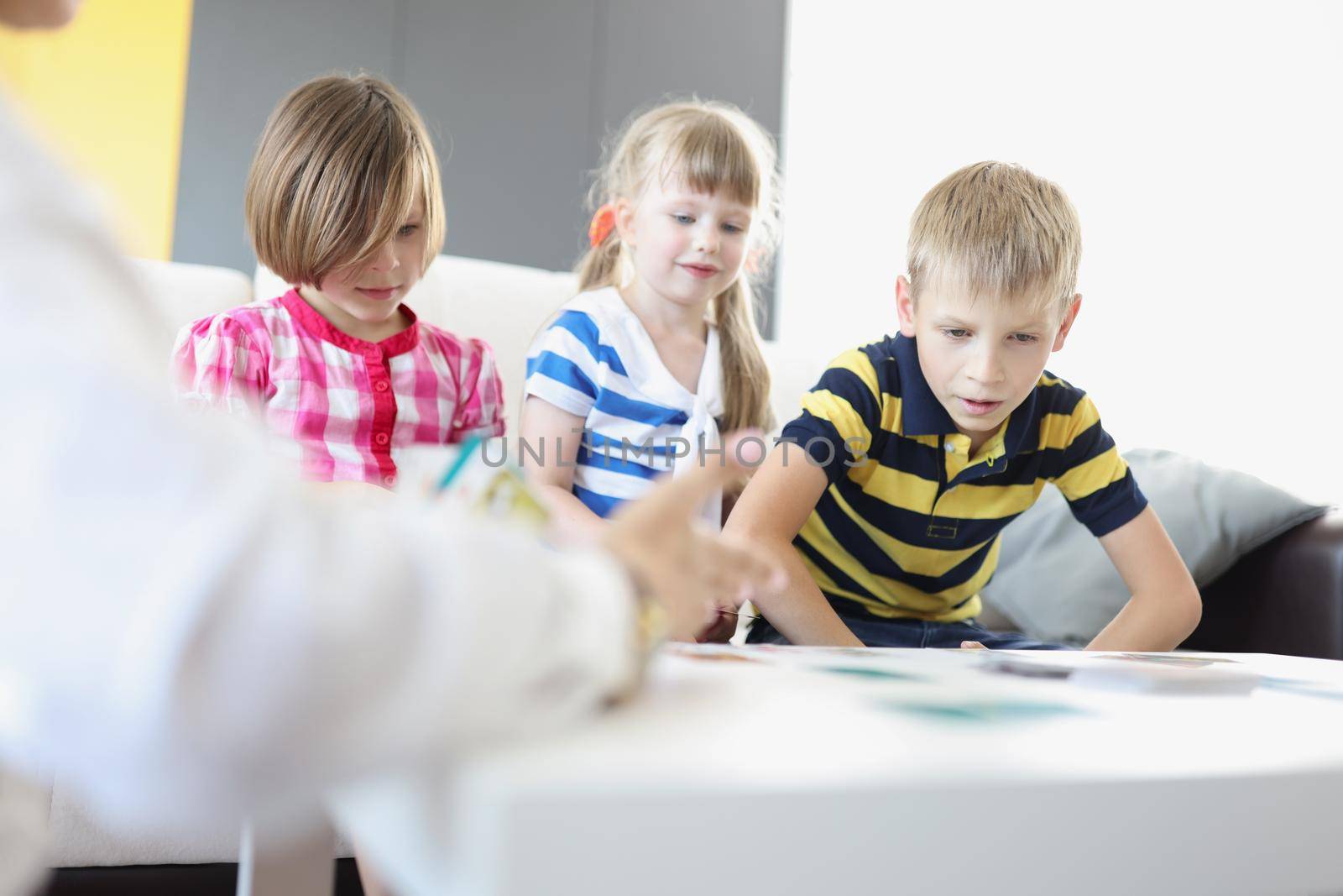 Kids sitting on sofa and play card game together for development by kuprevich