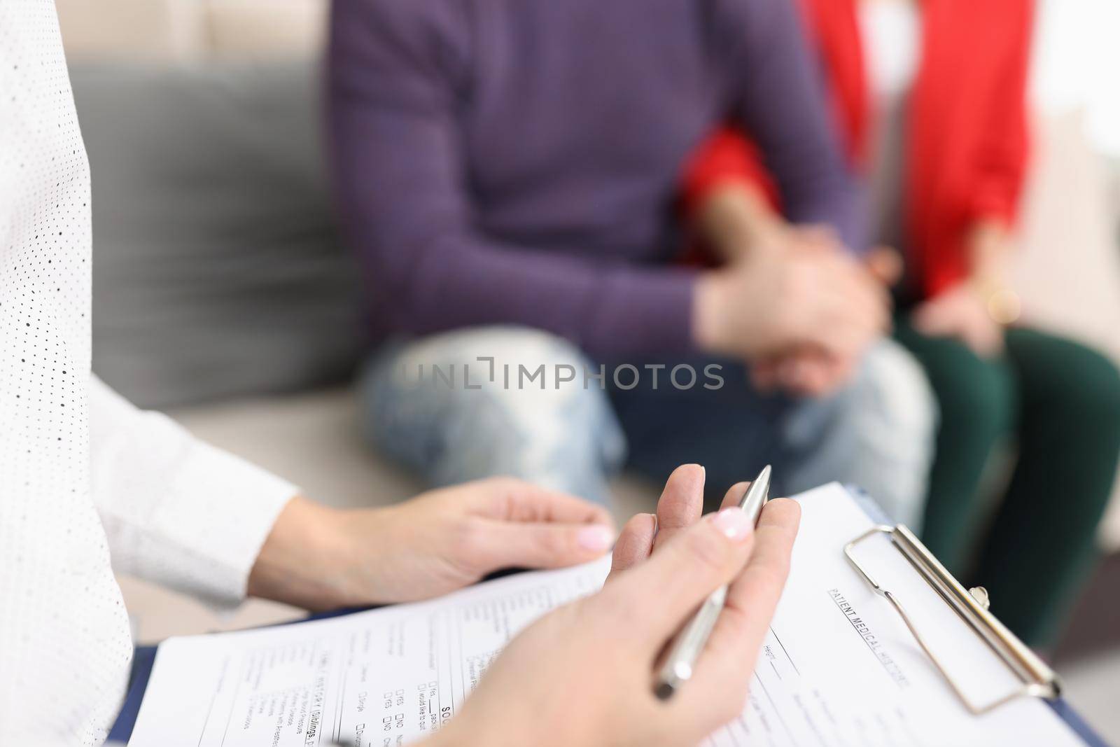 Close-up of doctor hold clipboard with patient medical history paper for couple. Qualified worker examine ask questions clients. Medicine, clinic concept