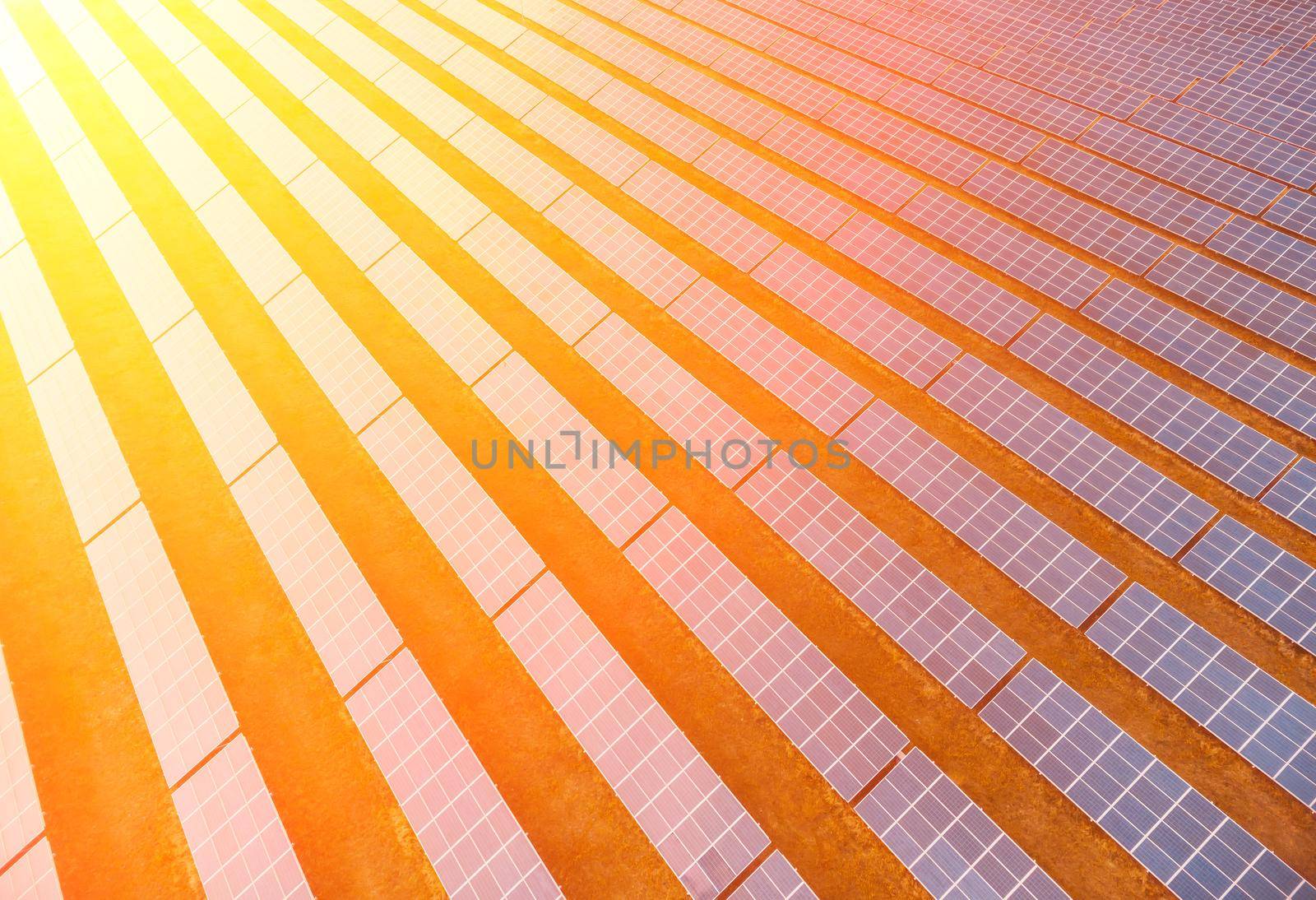 Aerial top view of a solar panels power plant. Photovoltaic solar panels at sunrise and sunset in countryside from above. Modern technology, climate care, earth saving, renewable energy concept