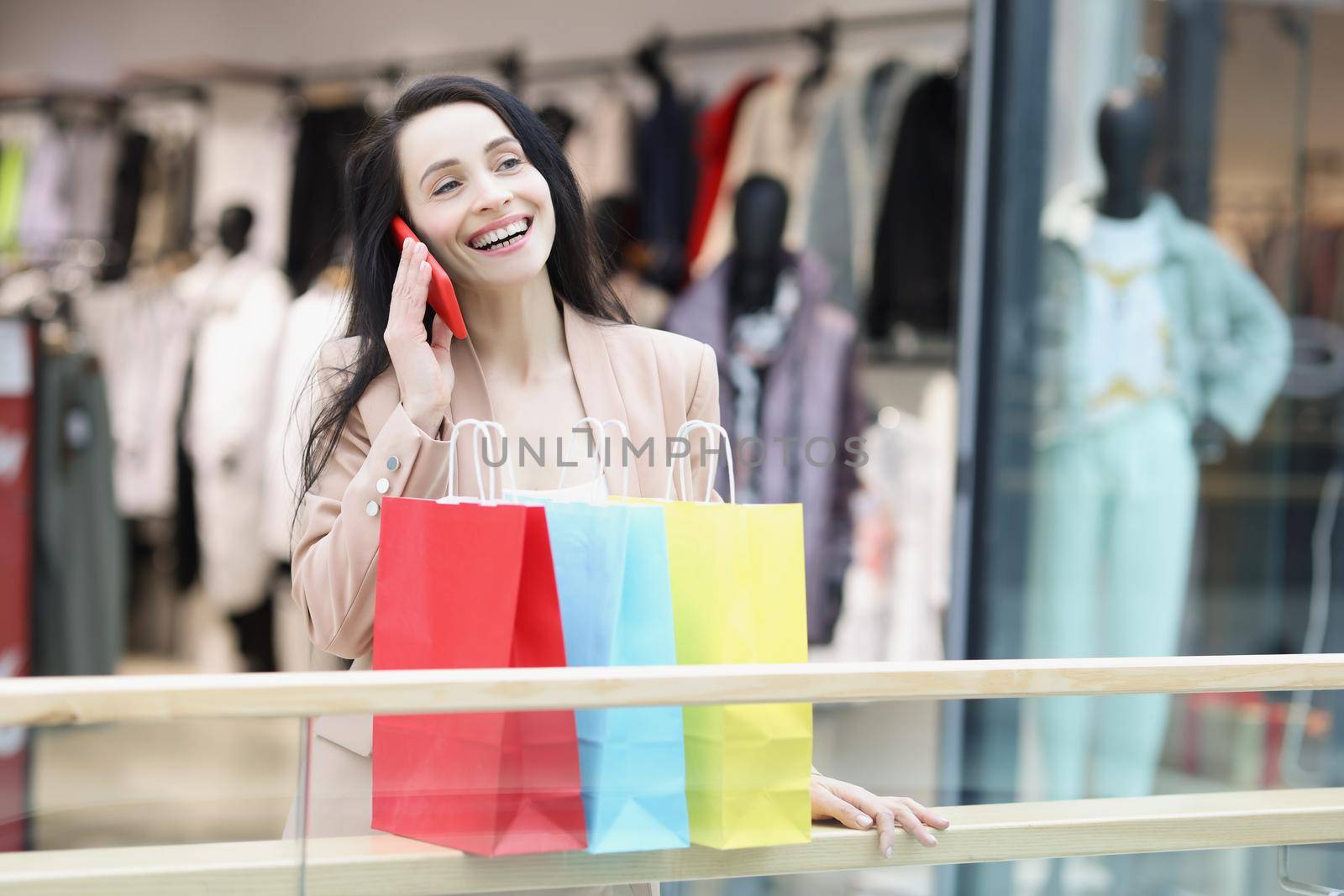 Portrait of young woman shopaholic smiling and tell to friend on call about sales. Girl carry many packs with clothes. Big sale, shopping, discount concept