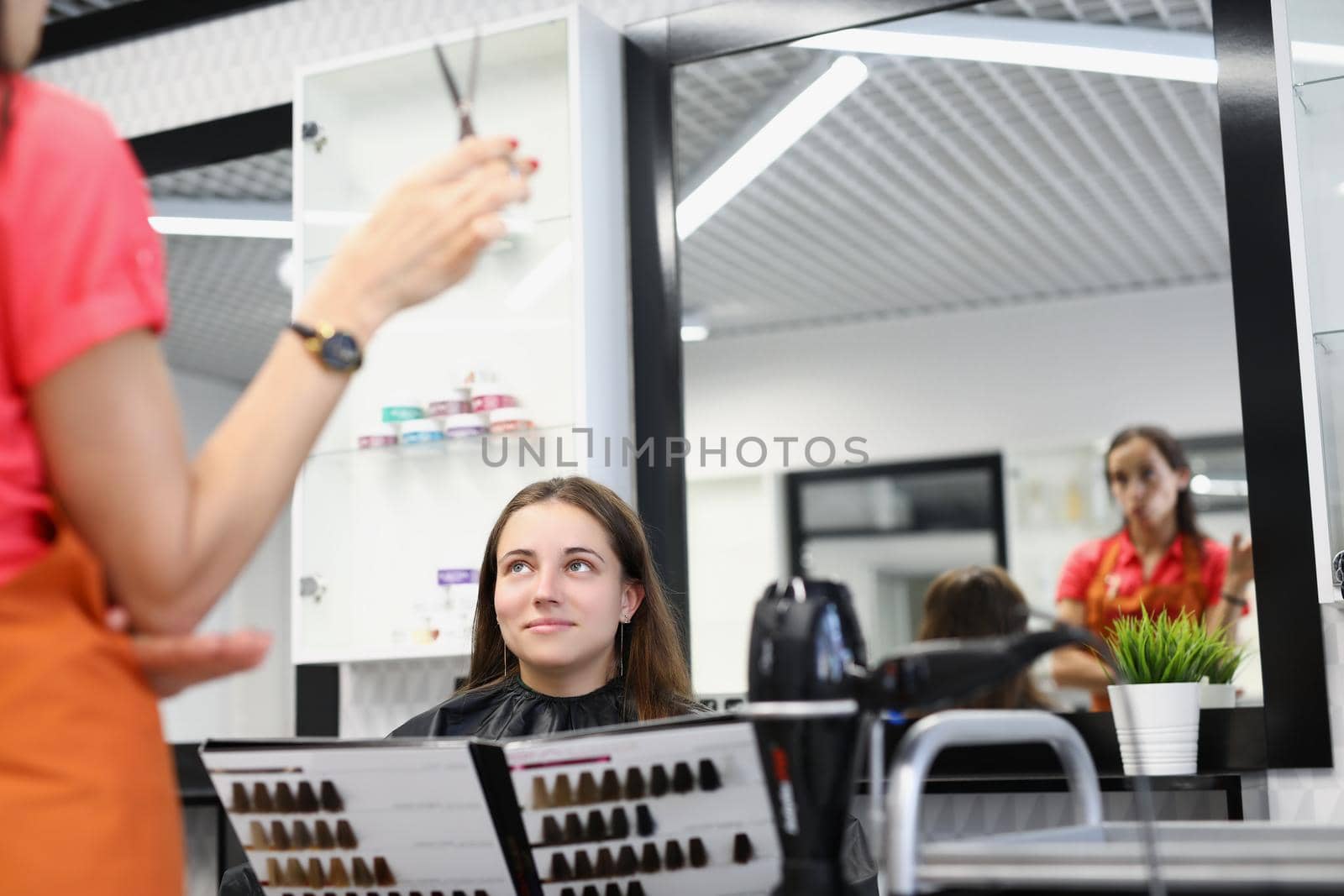 Portrait of pretty woman client hold palette of colours for hair dye at hairdresser appointment. Beauty treat at professional master. Image change concept