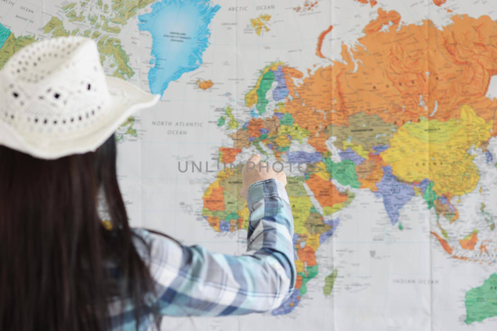 Close-up of woman point on world map with finger and decide what country to go next. Young female traveler explore world. Adventure, tourist, plan concept