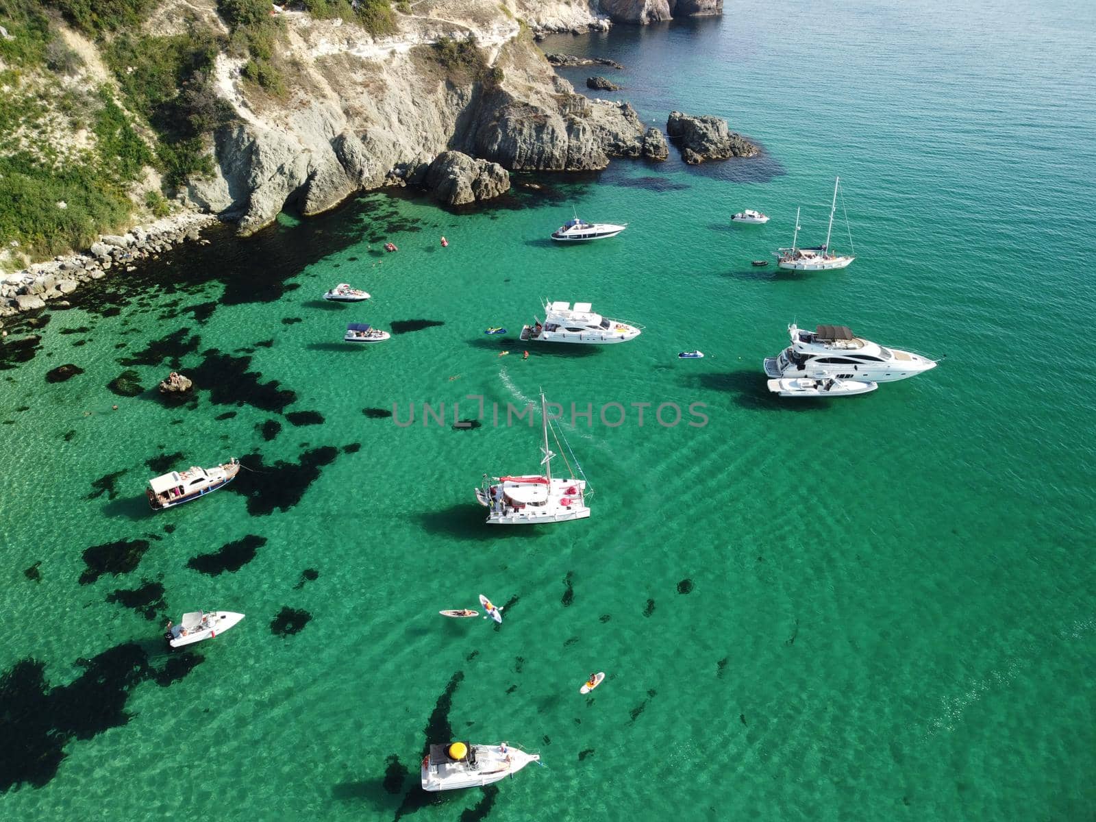 Sea landscape with rocky coastline on sunset time with cloudy sky. Yachts in the Sea on a background of rocky shores. The concept of perfect place for summer travel and rest.
