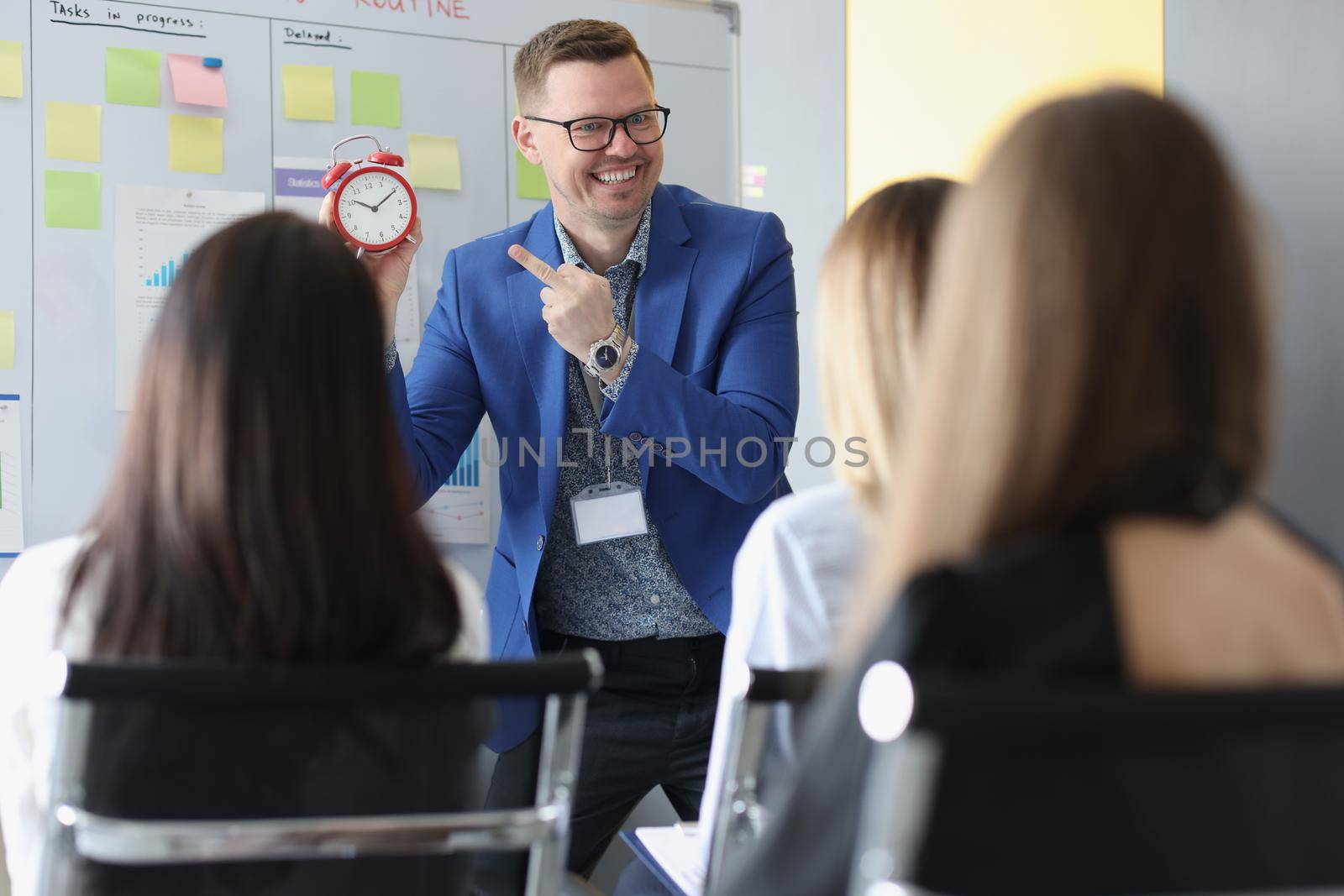 Portrait of man speech giver stand in from of colleagues and explain that time is money. Training for company workers, skills development. Business concept