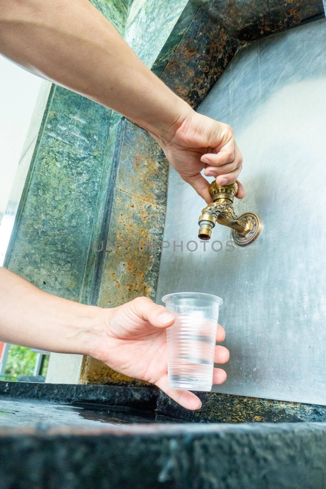 Pouring mineral thermal water into the disposable cup at the pump-room, close-up. narzan spring in Kislovodsk, Russia. High quality photo