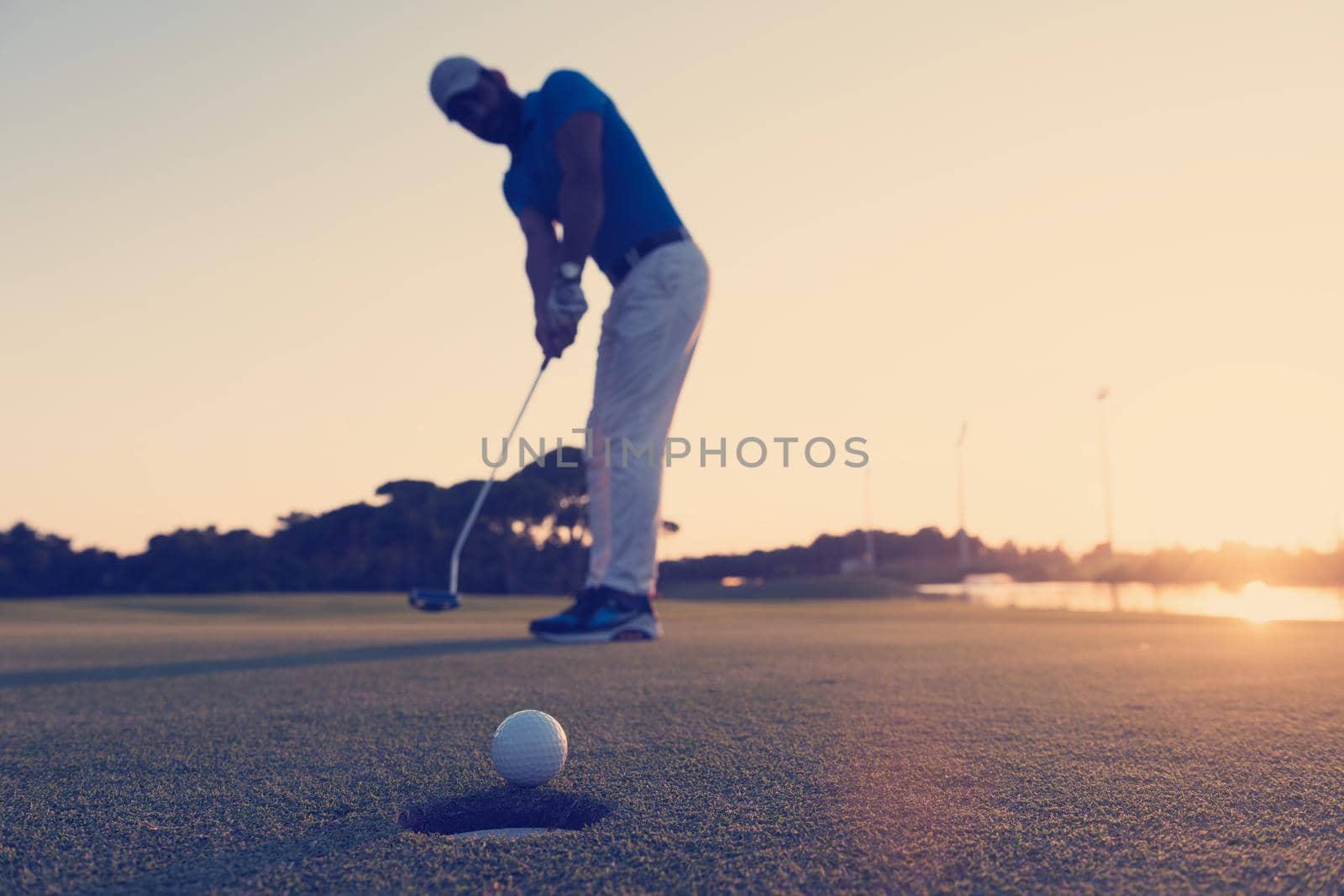golfer  hitting shot at golf course by dotshock