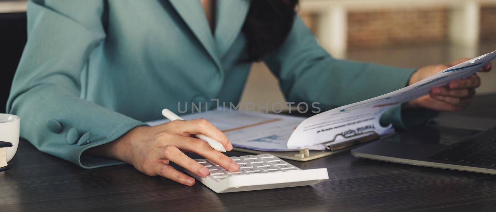 Close up asian accountant working and analyzing financial reports project accounting with chart graph and calculator.