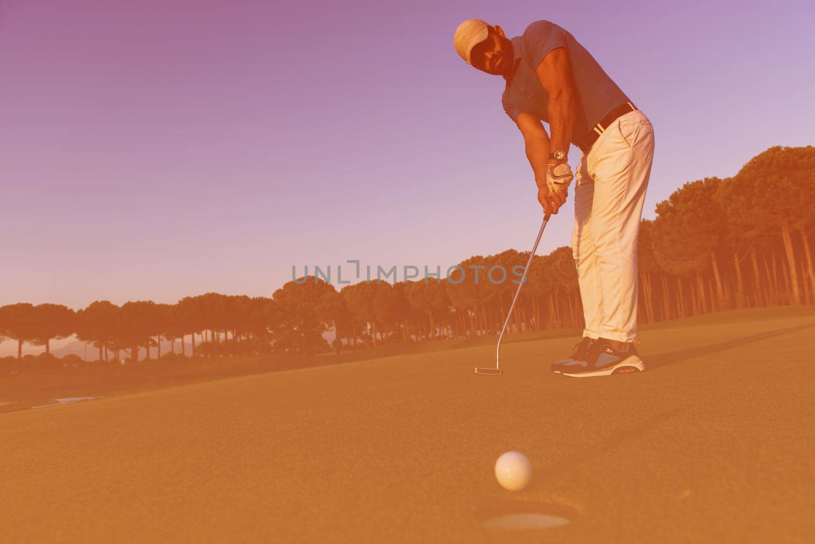 golfer  hitting shot at golf course by dotshock