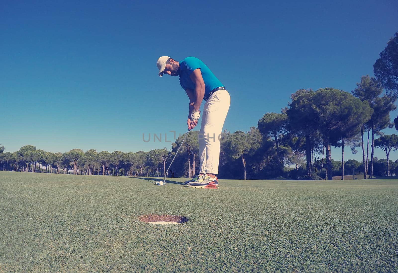 golf player hitting shot with driver on course at beautiful sunny day