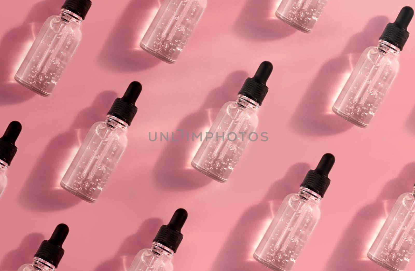 Transparent glass dropper bottle with air bubbles pattern on pink background in sunlight. Pipette with fluid hyaluronic acid, serum, retinol. Cosmetics and healthcare concept. Luxury beauty product