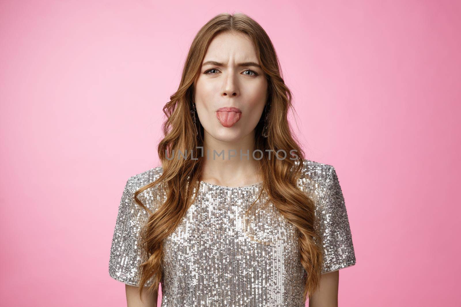 Moody immature cute glamour rich spoiled girl stick out tongue expressing dislike reluctance cringing frowning disappointed, offended boyfriend, standing dissatisfied pink background.
