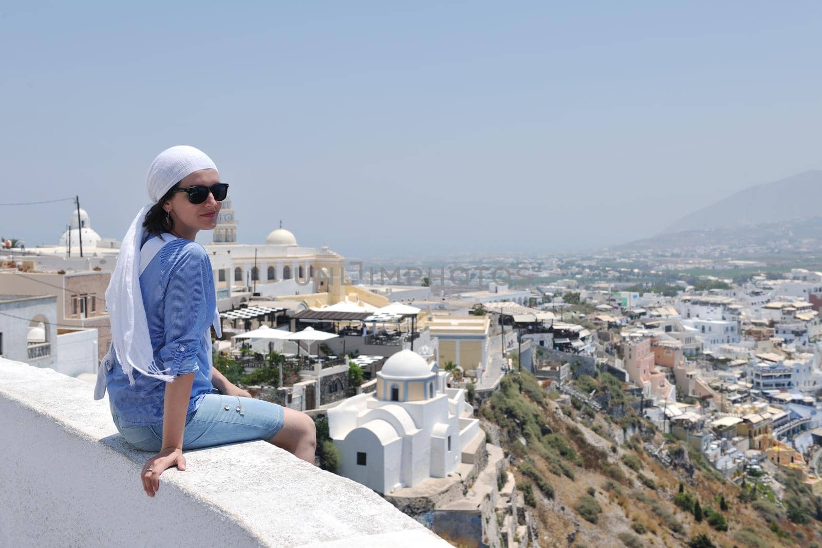 Beautiful young Greek woman in fashion clothes have fun at n the streets of Oia, Santorini, Greece