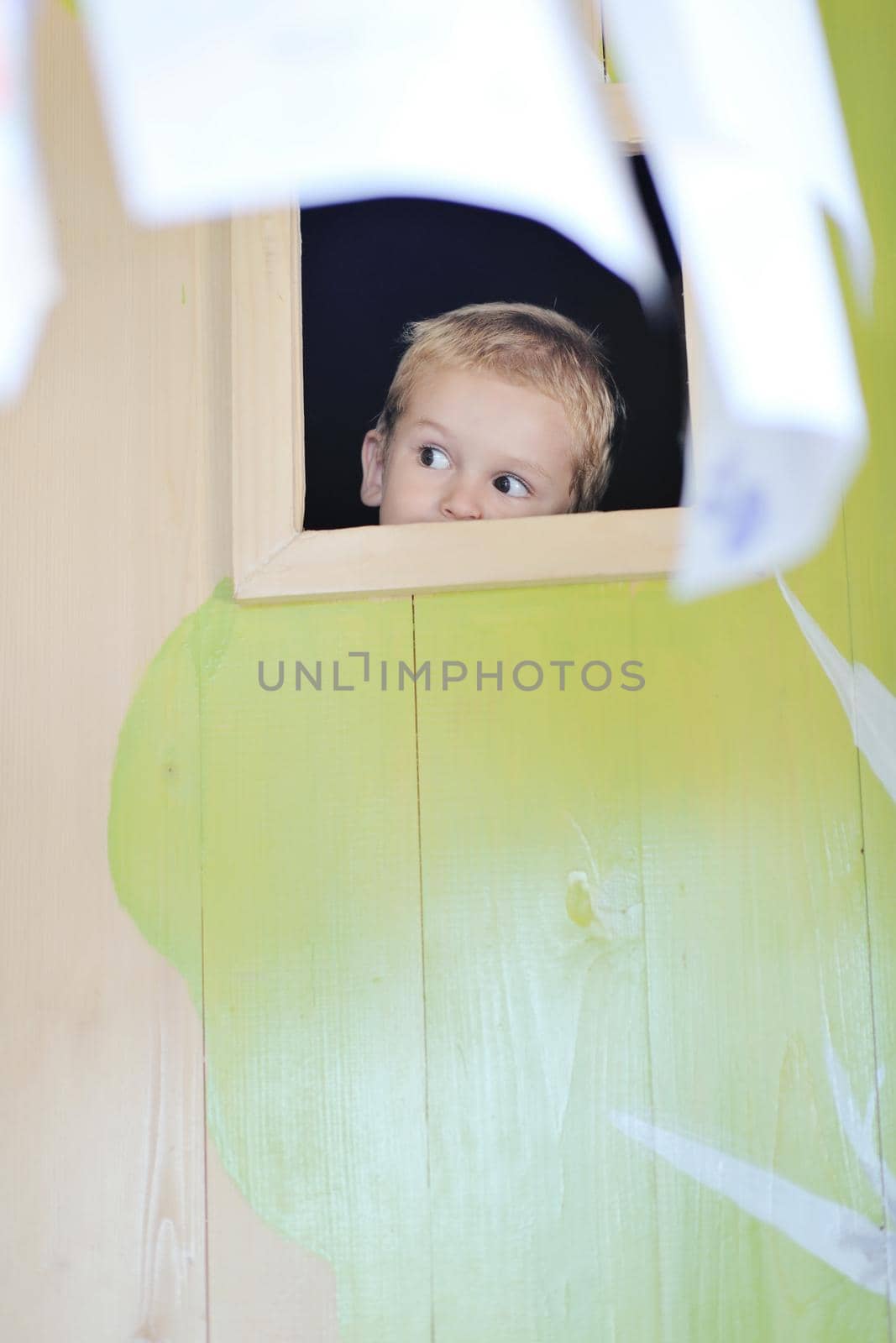 happy cute child in a wooden window at playground