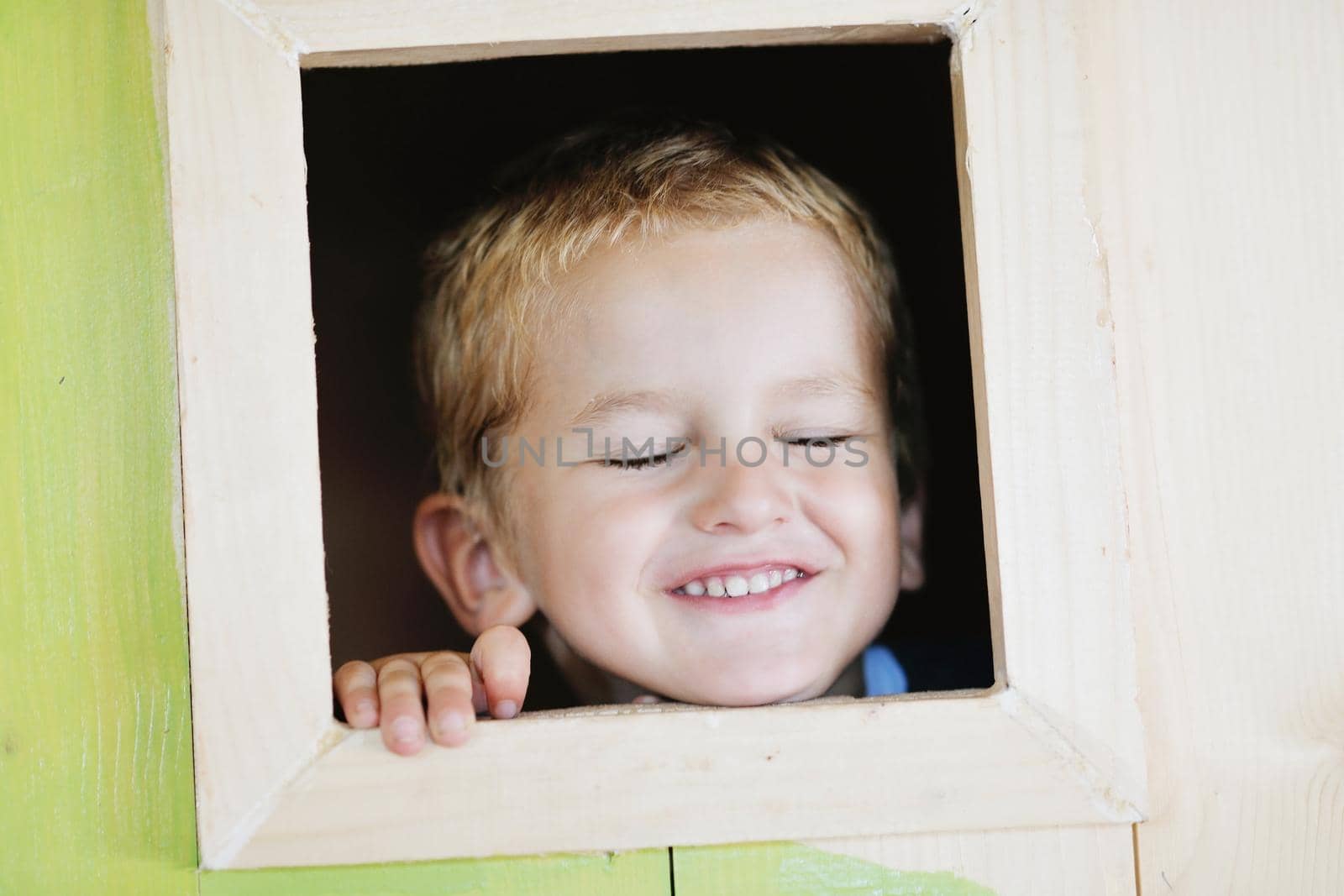 happy cute child in a wooden window at playground