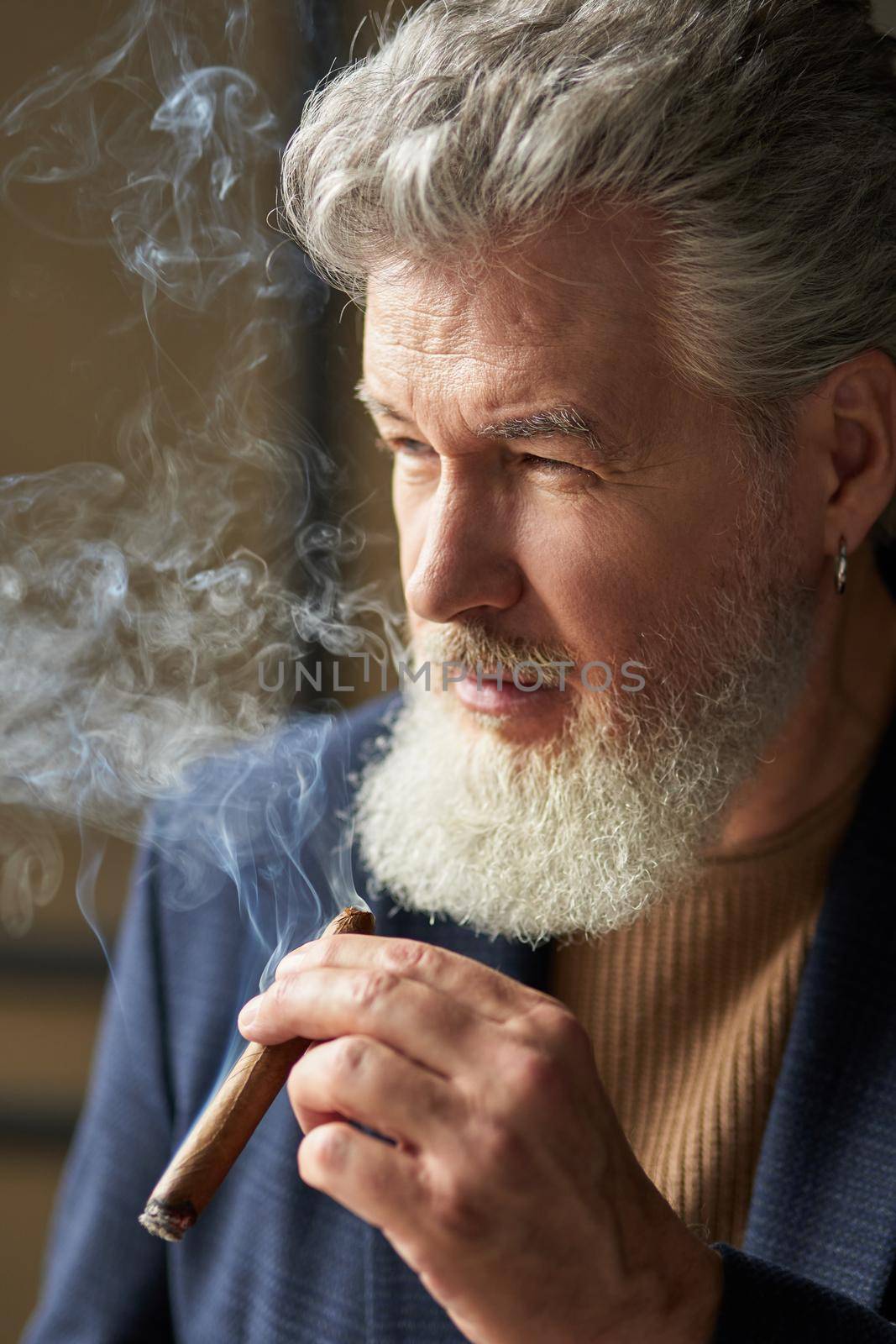 Close up portrait of serious grey haired mature man looking away while smoking cigar. Lifestyle, success, people concept