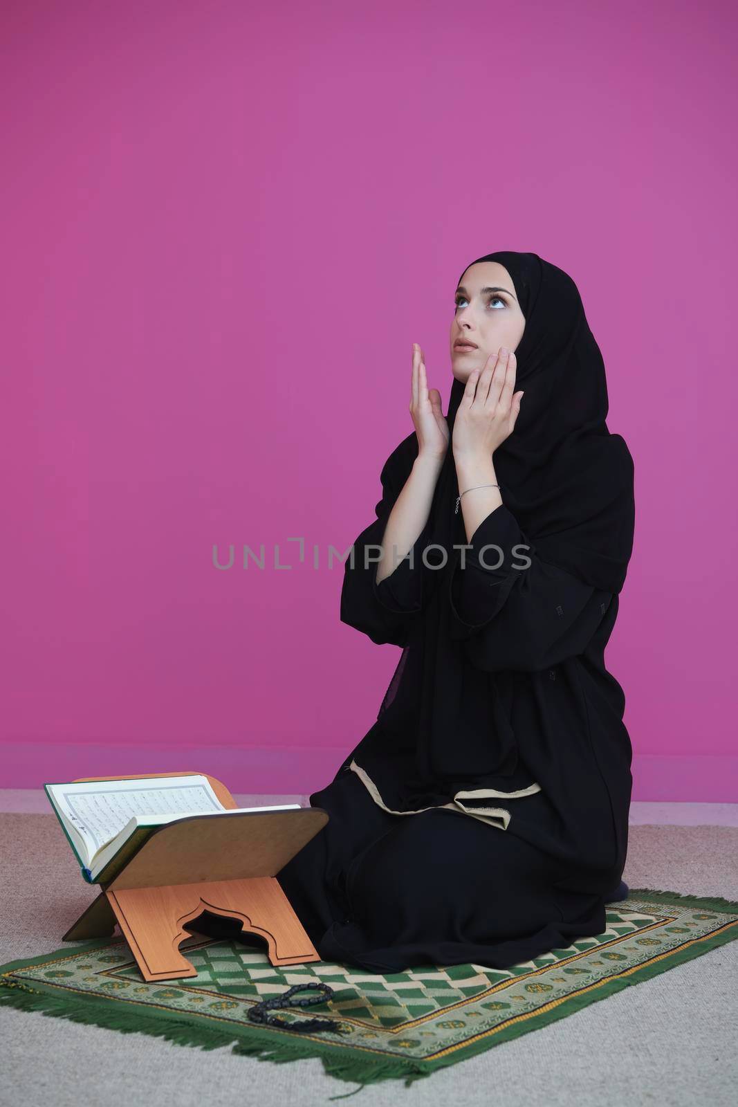 Middle eastern woman praying and reading the holy Quran, public item of all muslims. Education concept of Muslim woman studying The holy Quran at home or mosque in ramadan month.