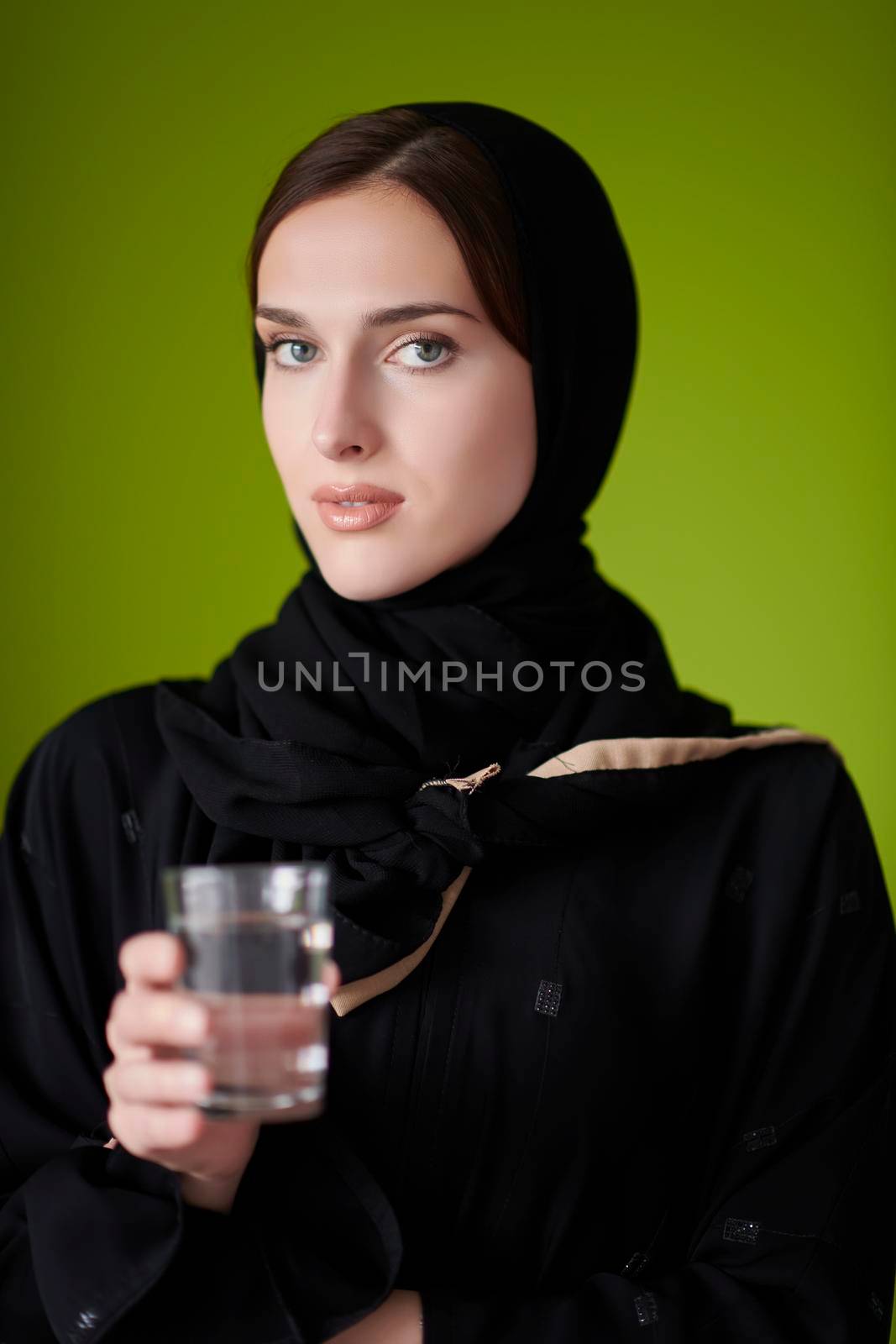 Middle eastern woman in abaya holding a glass of water by dotshock