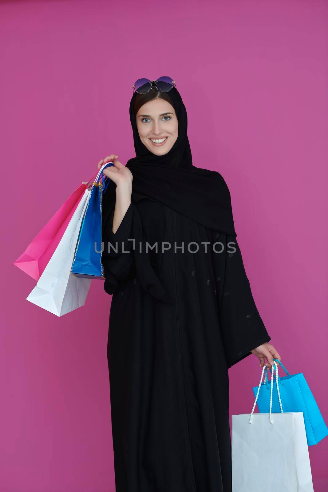 Happy muslim girl posing with shopping bags. Arabic woman wearing traditional black clothes and sunglasses representing rich and  luxurious lifestyle