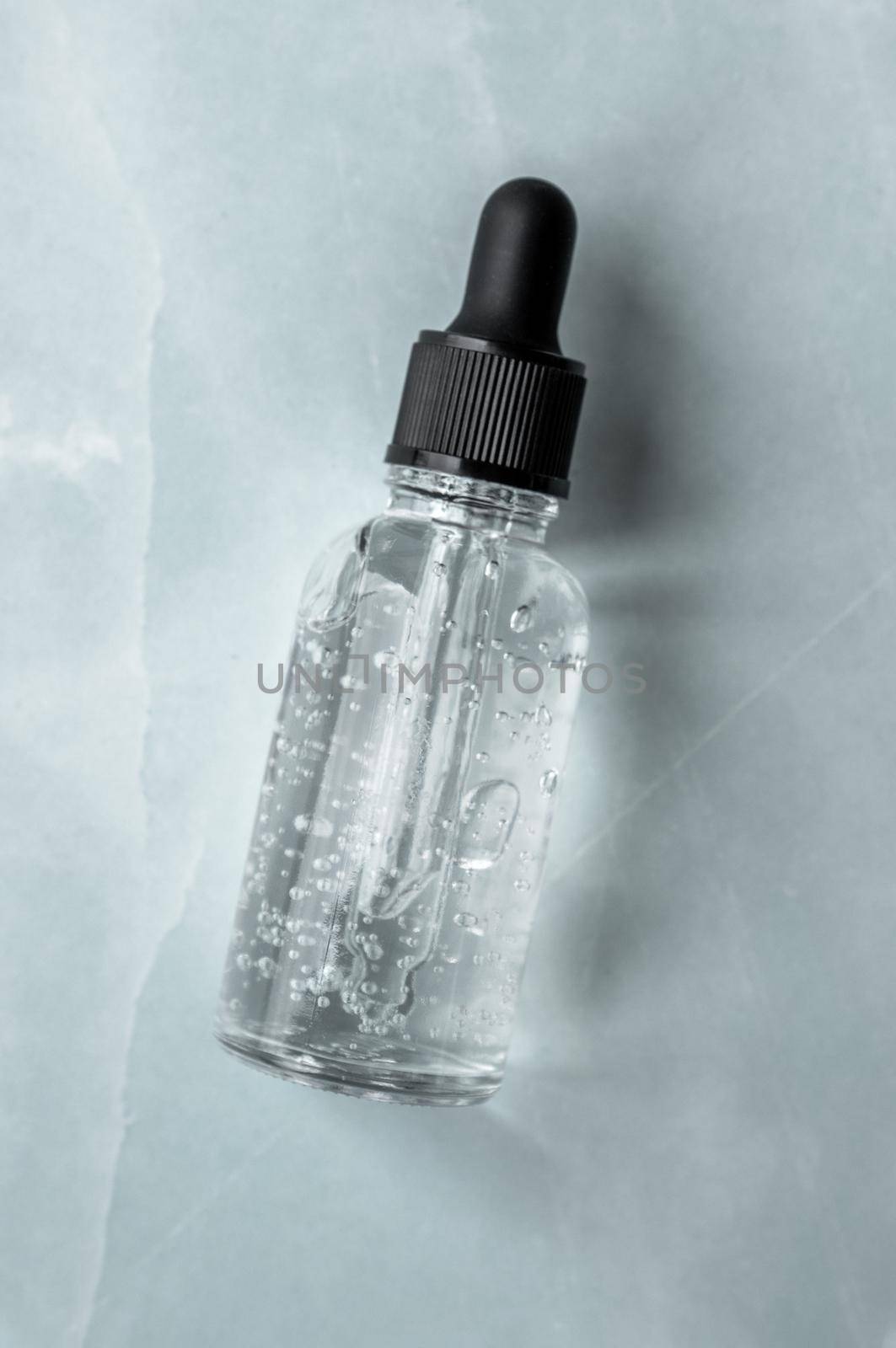 Transparent glass dropper bottle with air bubbles on marble background. Pipette with fluid hyaluronic acid, serum, retinol or oil. Cosmetics and healthcare concept. Flat lay. Luxury beauty product