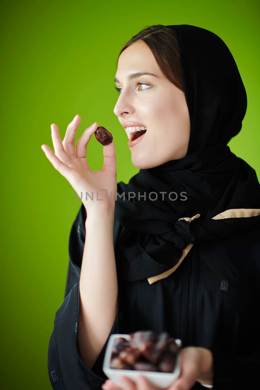 Young muslim girl wearing traditional muslim clothes holding dried dates. Arab girl representing iftar time, holy fasting month, Ramadan Kareem