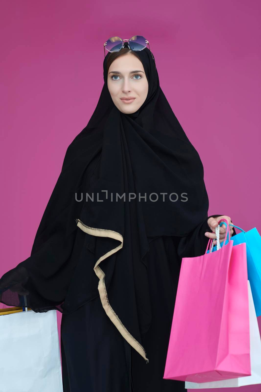 Happy muslim girl posing with shopping bags. Arabic woman wearing traditional black clothes and sunglasses representing rich and  luxurious lifestyle