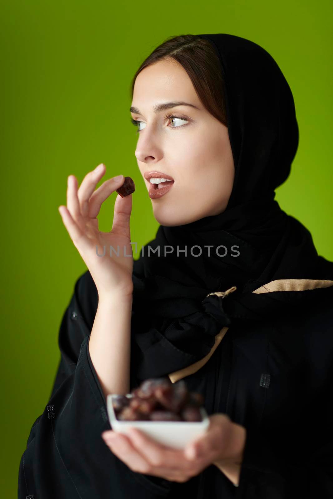 Young muslim girl wearing traditional muslim clothes holding dried dates by dotshock