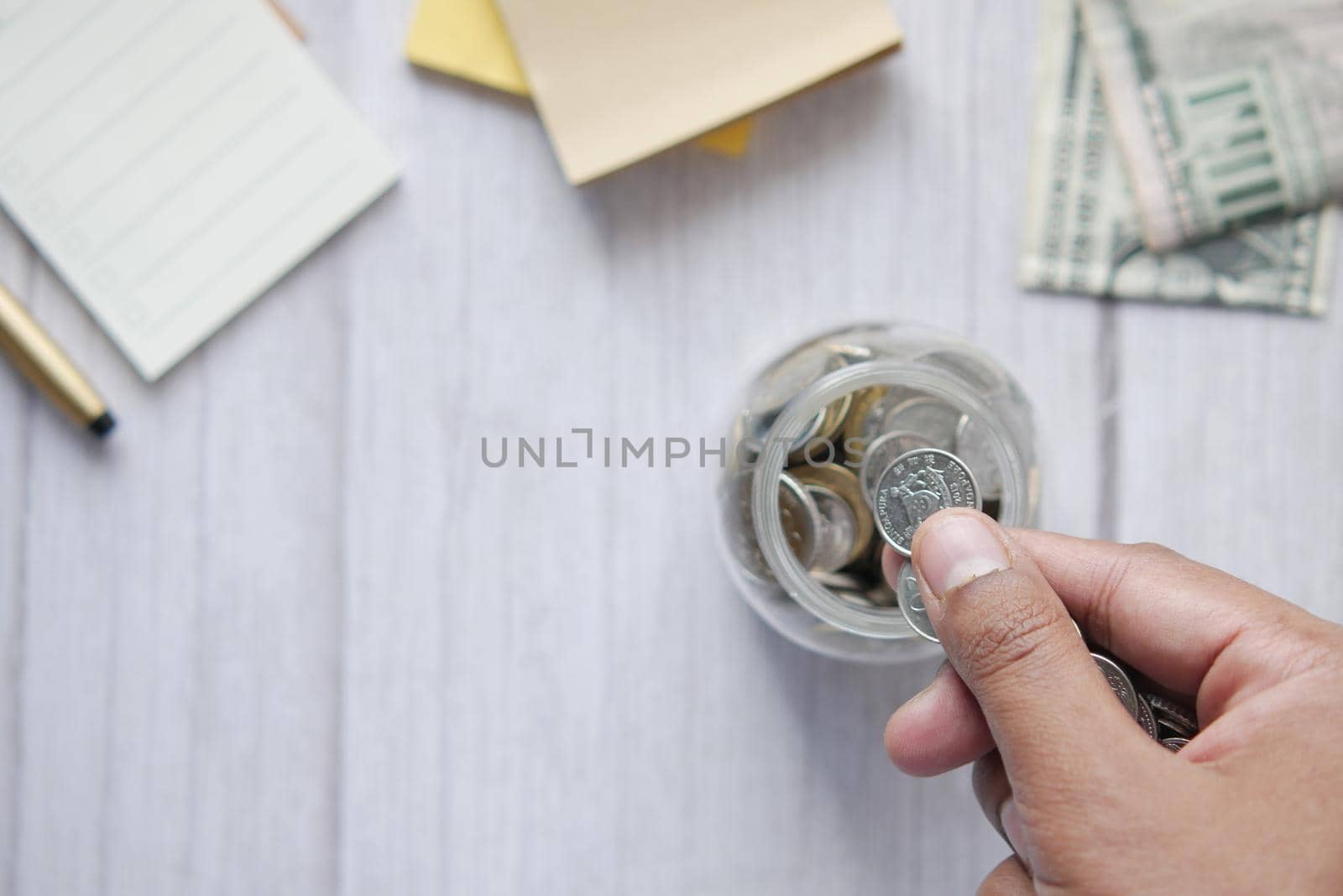 young man saving coins in a jar white sited .